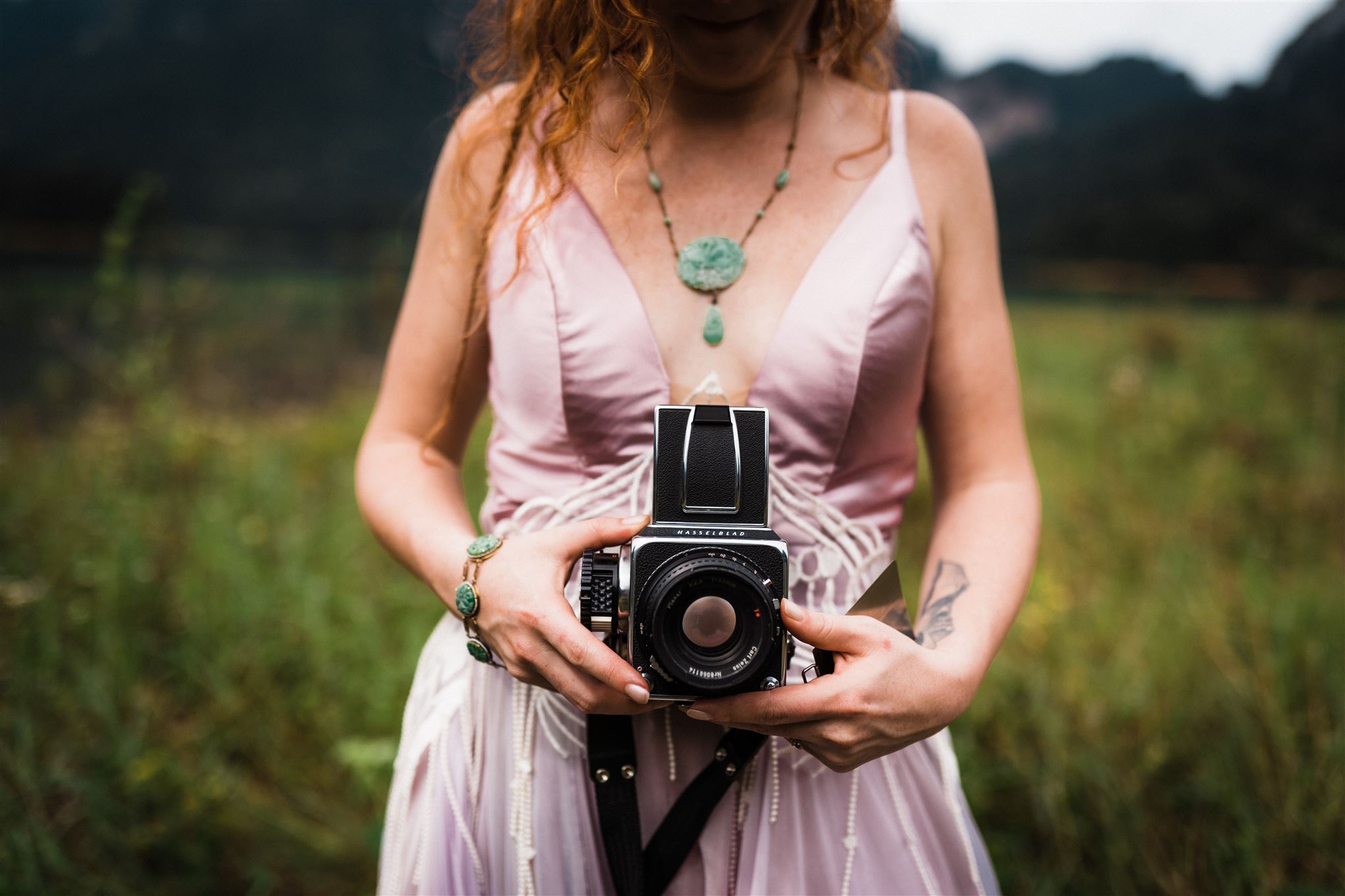 Bride holding a film camera wearing a pink elopement dress