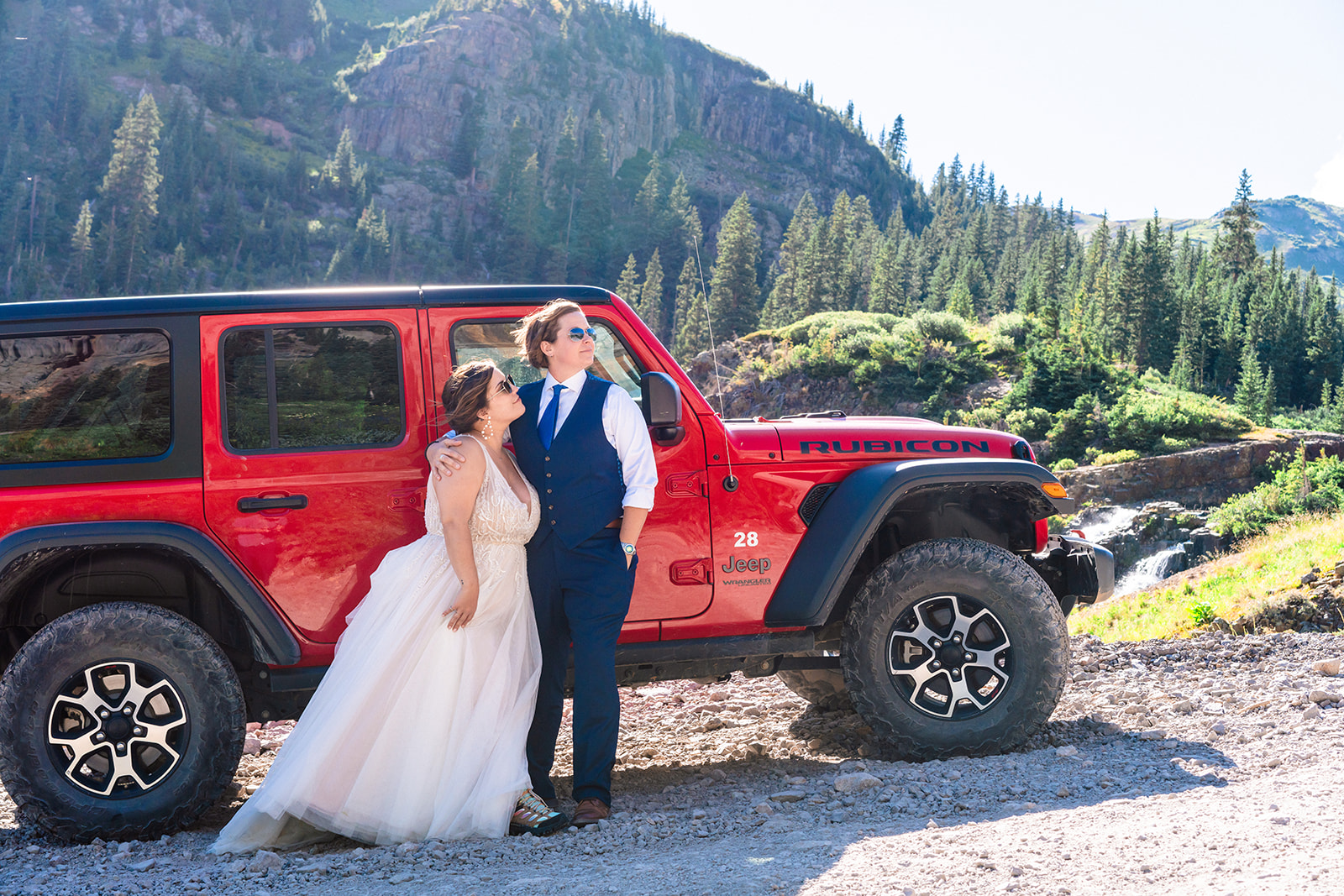 Lesbian couple standing near red Jeep
