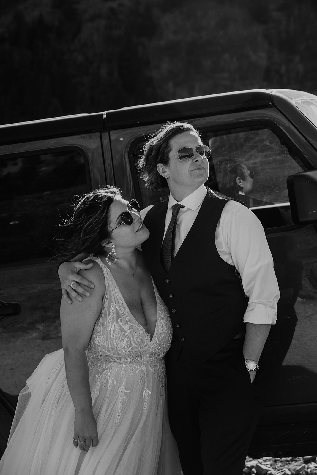 Black and white photo of LGBTQIA+ Couple standing in front of a Jeep