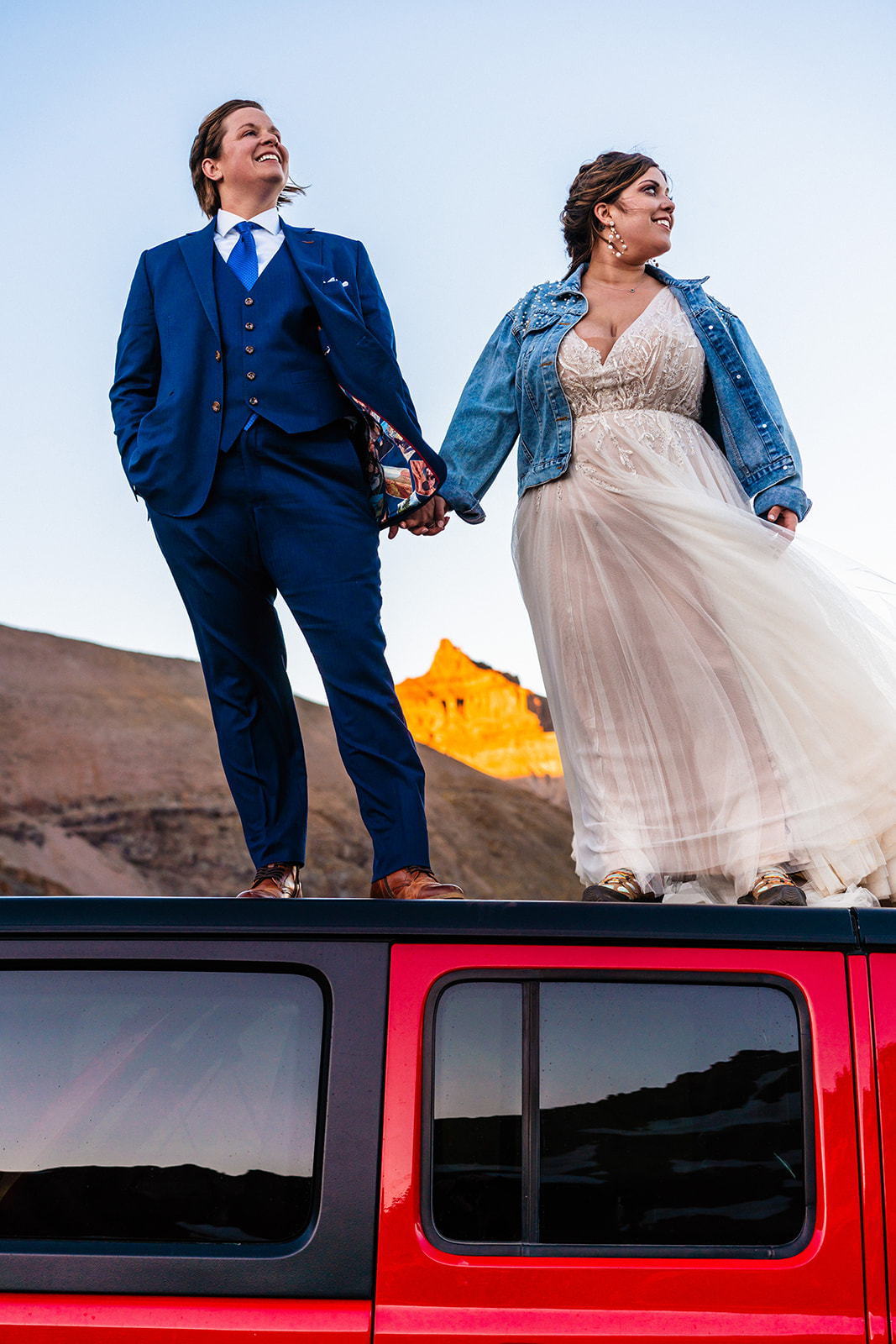 Lesbian couple standing on their red Jeep for their off-road elopement