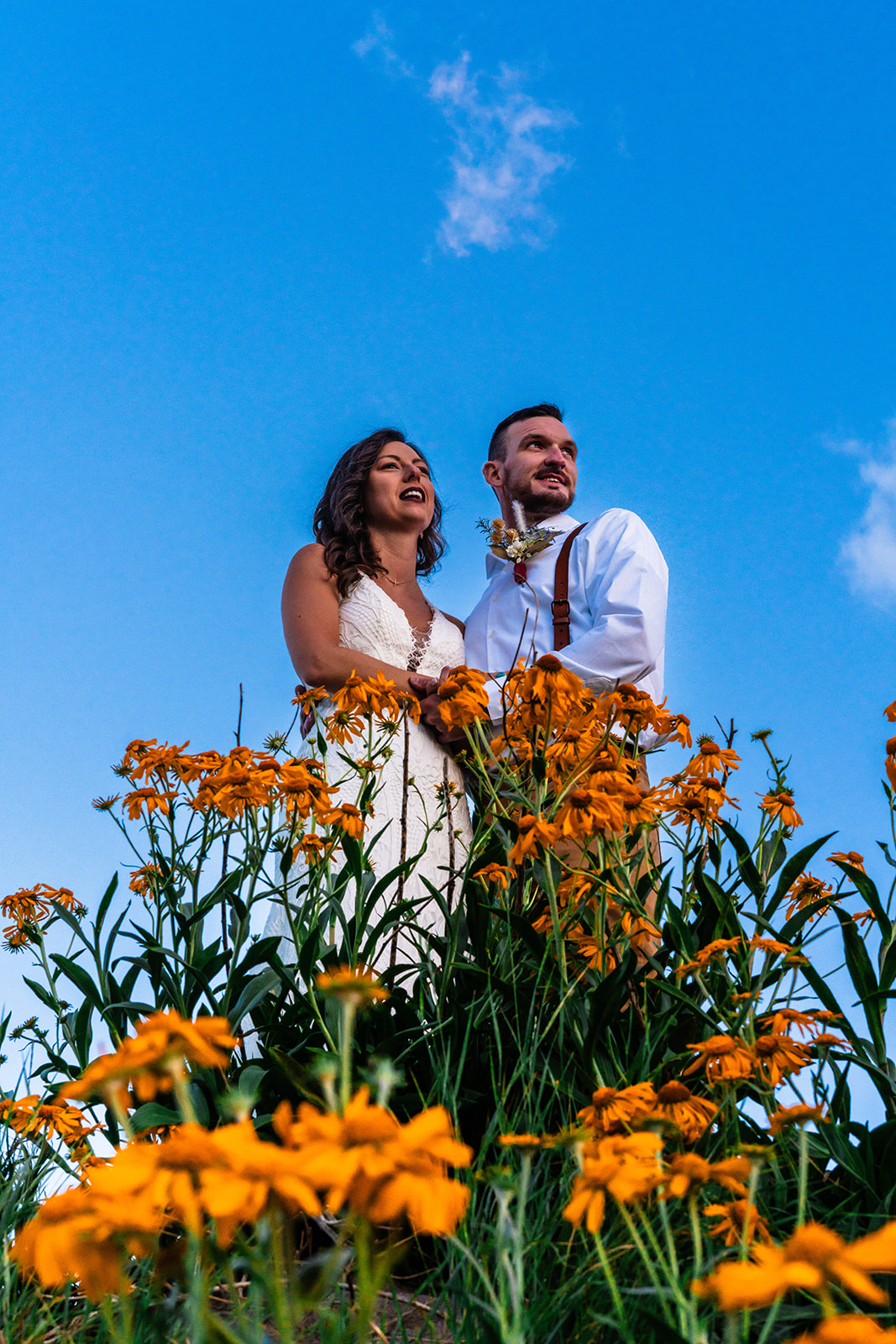 Bride and groom looking off into the distance next to beautiful orange flowers