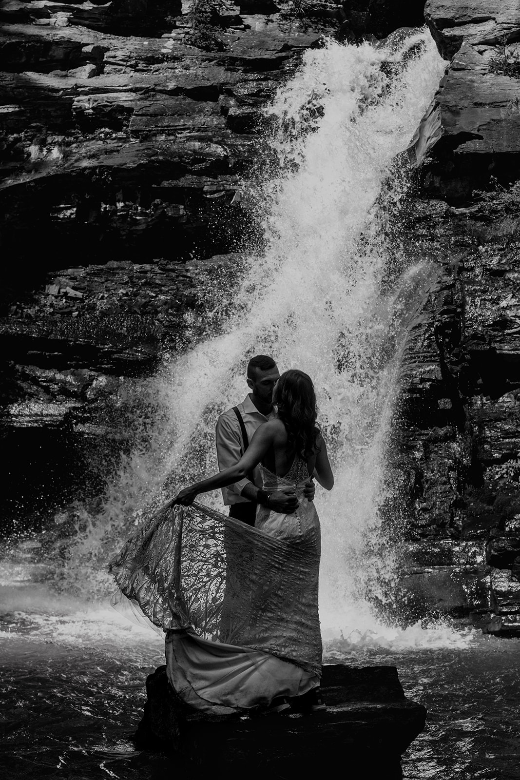 Black and white photo of Bride and groom dancing near waterfall in the San Juan Mountains