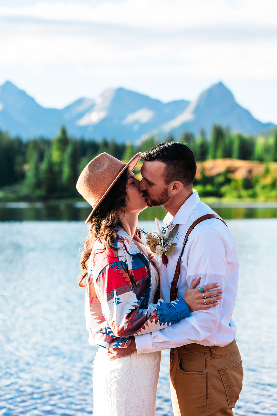 Bride and groom kissing near the shoreline of the San Juan mountains