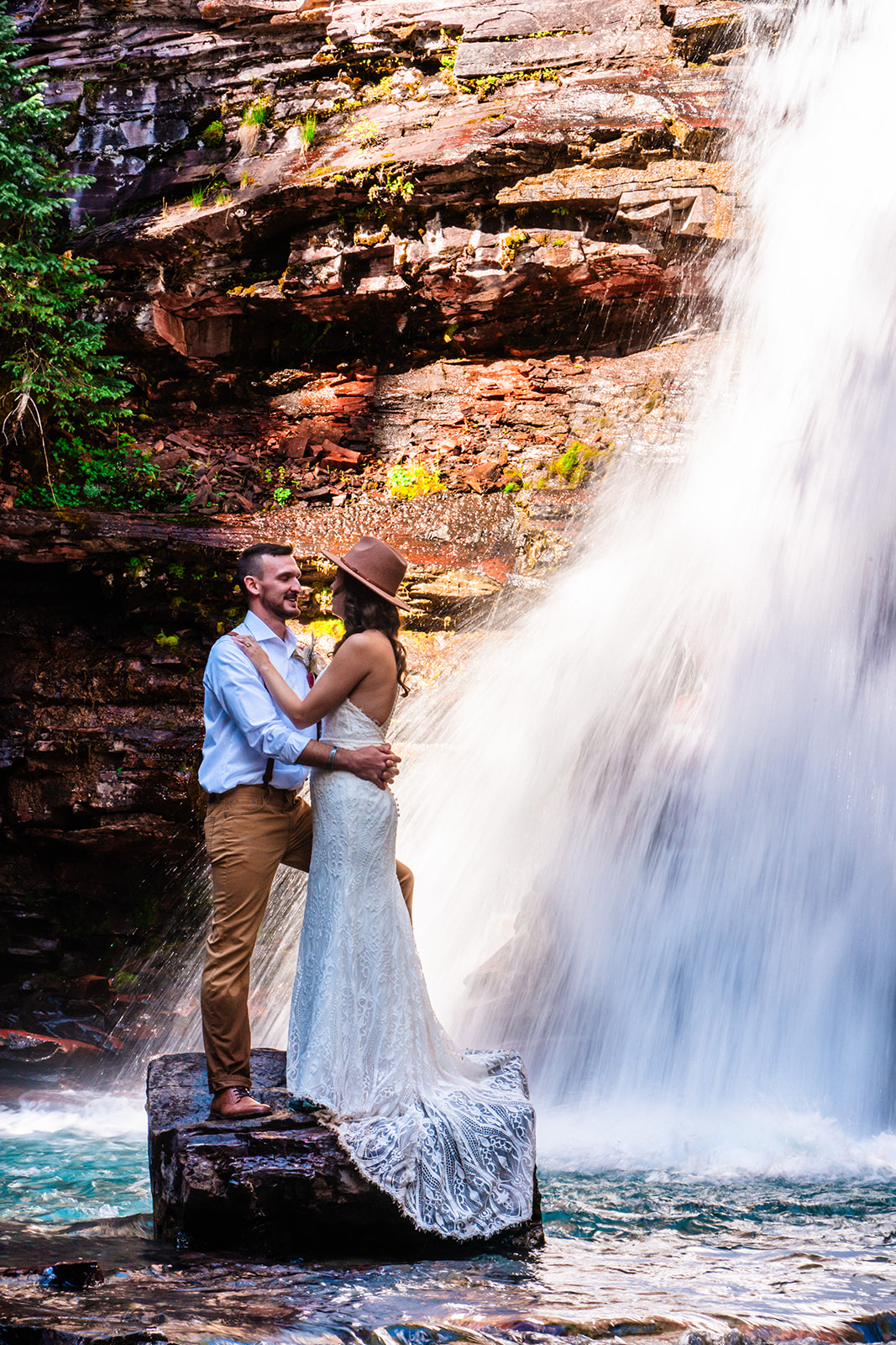 Bride and groom looking at one another endearingly next to a waterfall in the San Juan mountains