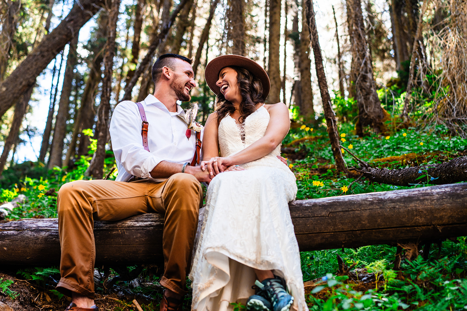 Bride and groom sitting on fallen tree in the forests of the San Juan mountains