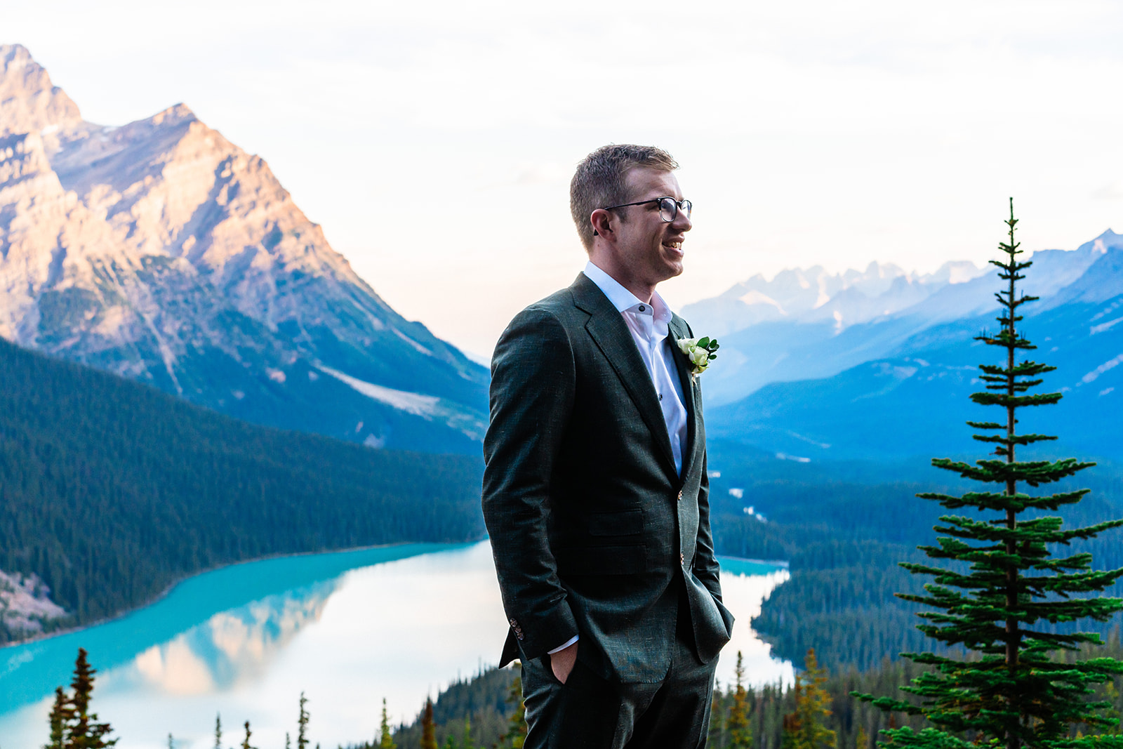 Groom posing in suite with the view of the Banff mountains
