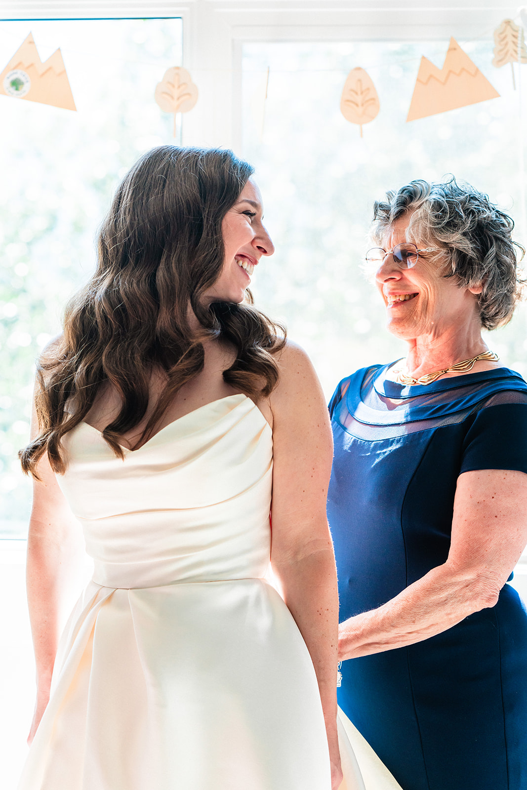 Mother of bride smiling helping bride get ready for her intimate wedding in Banff