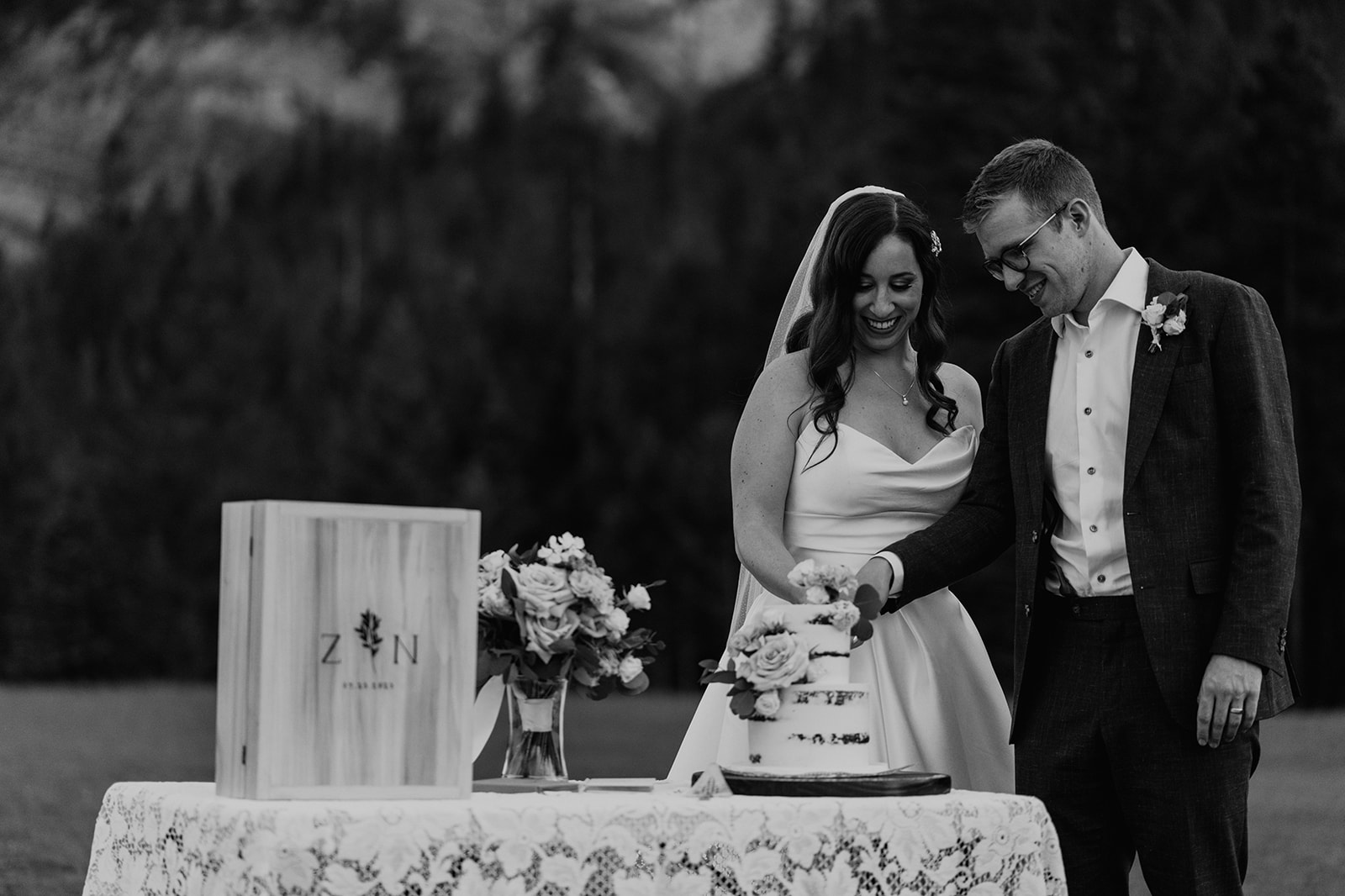 Black and white photo of Bride and groom cutting cake for their Banff Wedding