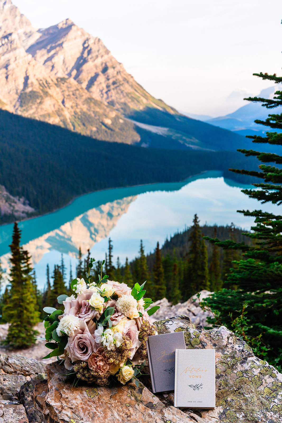 Bride and groom vows and floral bouquet with a view of Banff mountains and lake in the background