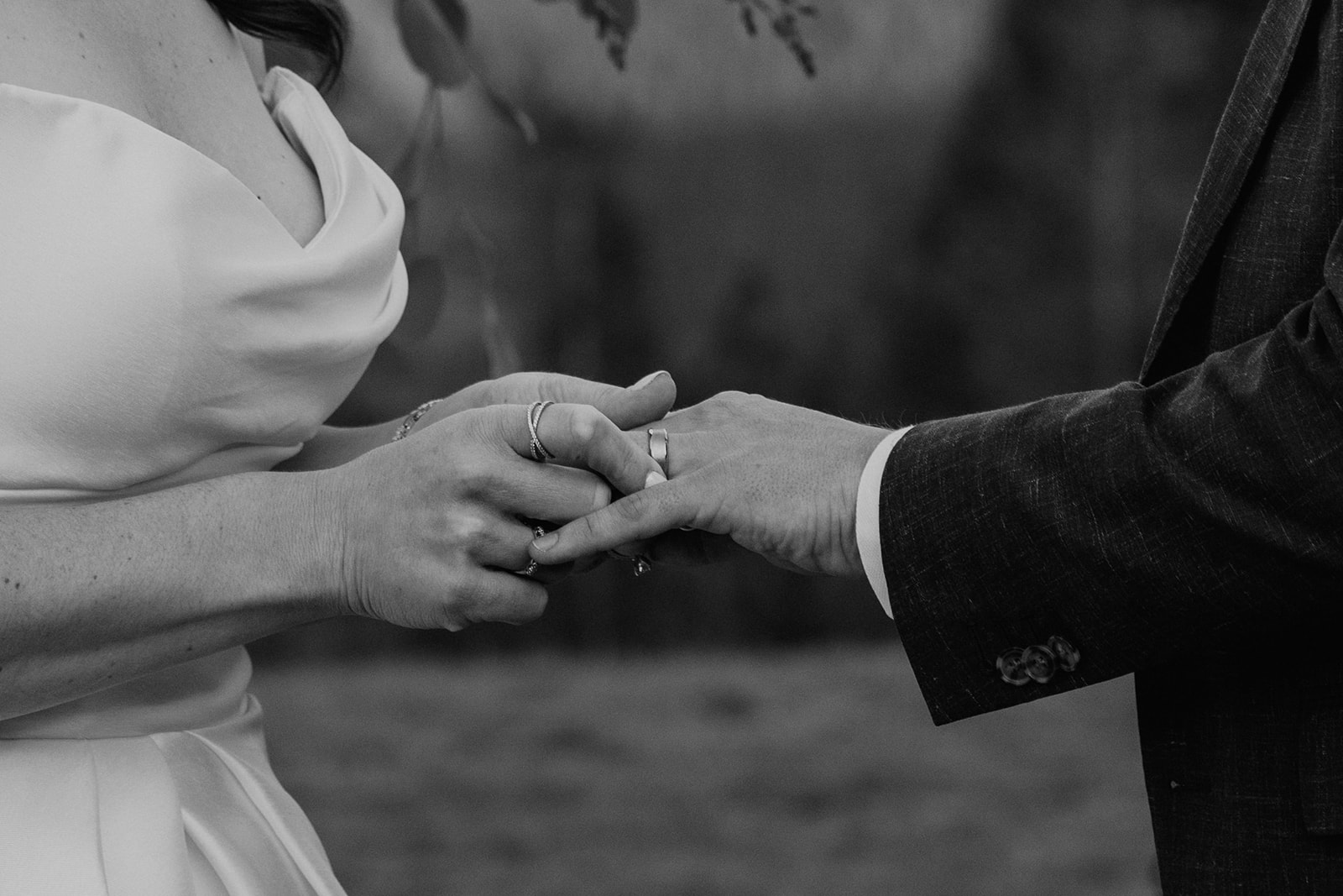 Black and white photo of bride and groom exchanging wedding rings