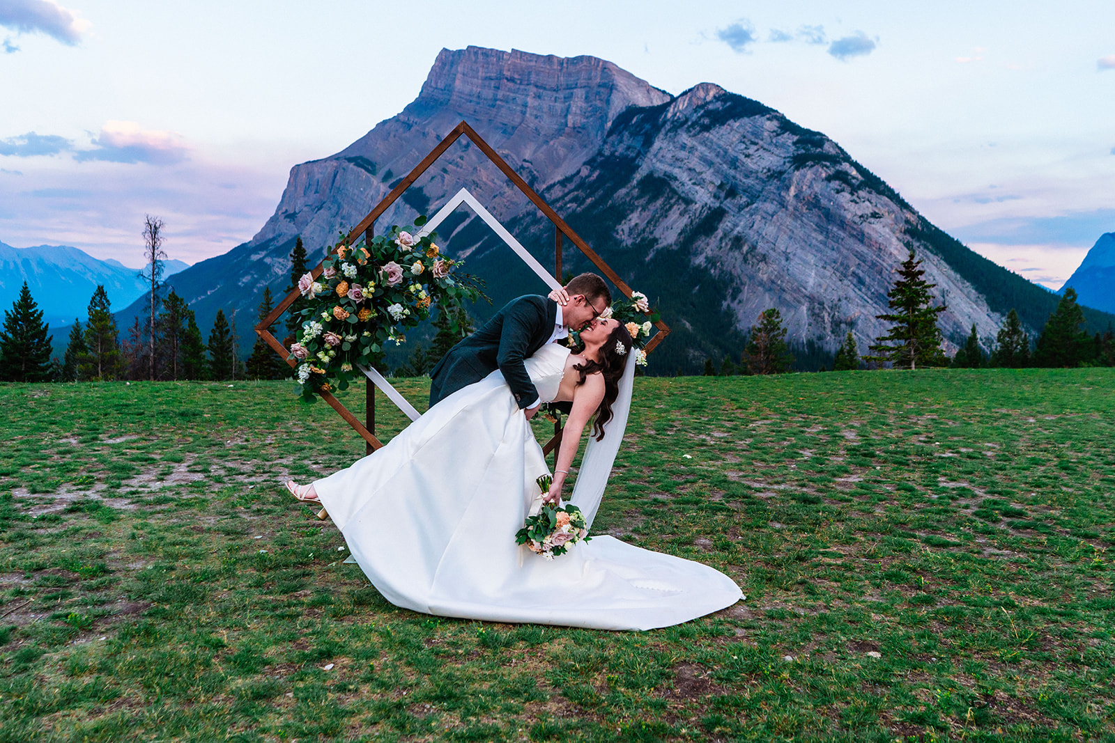 Bride and groom kissing in front of beautiful wooden arch