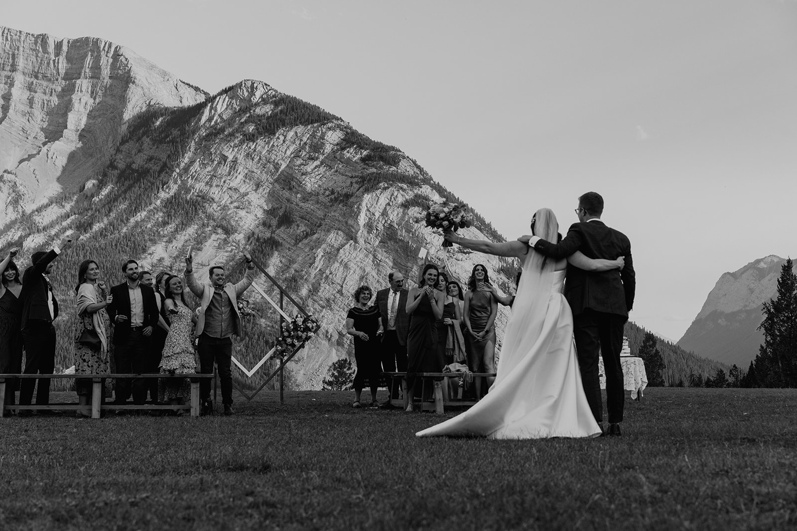 Black and white photo of bride and groom cheering after their intimate Banff wedding ceremony