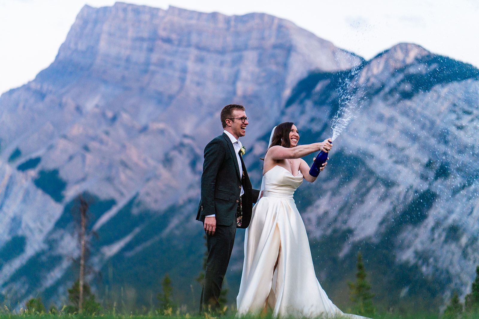 Bride and groom popping sparkling water on their Banff wedding day