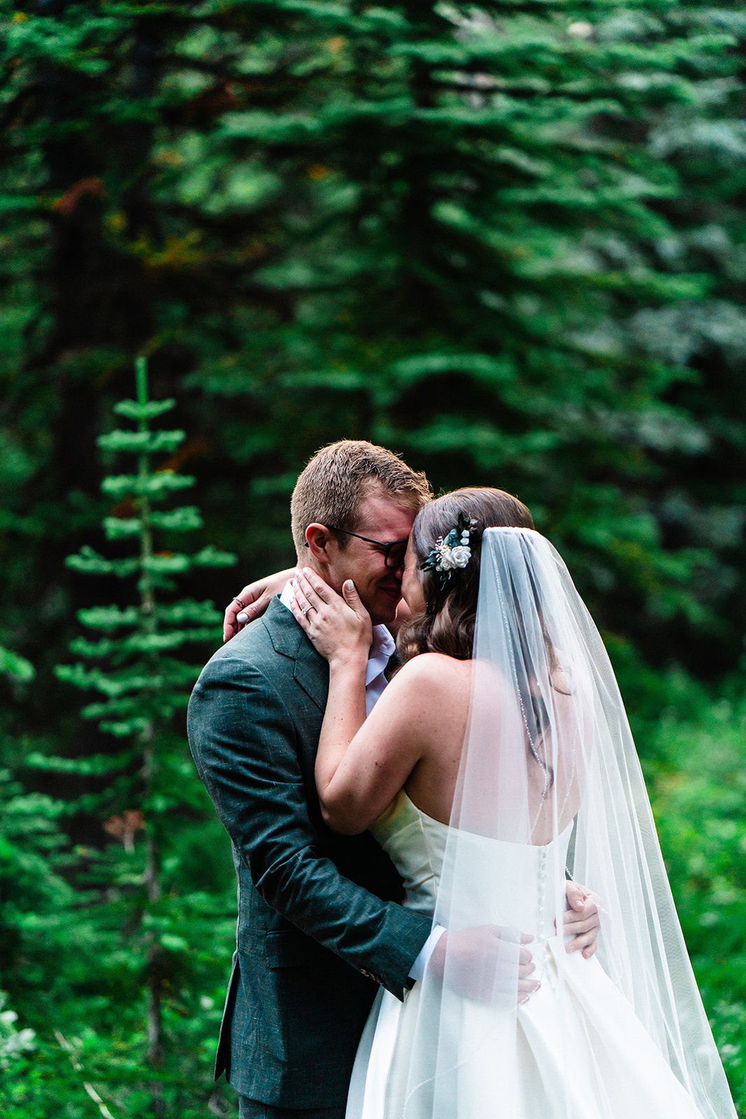 Bride and groom kissing one another in the forests of Banff