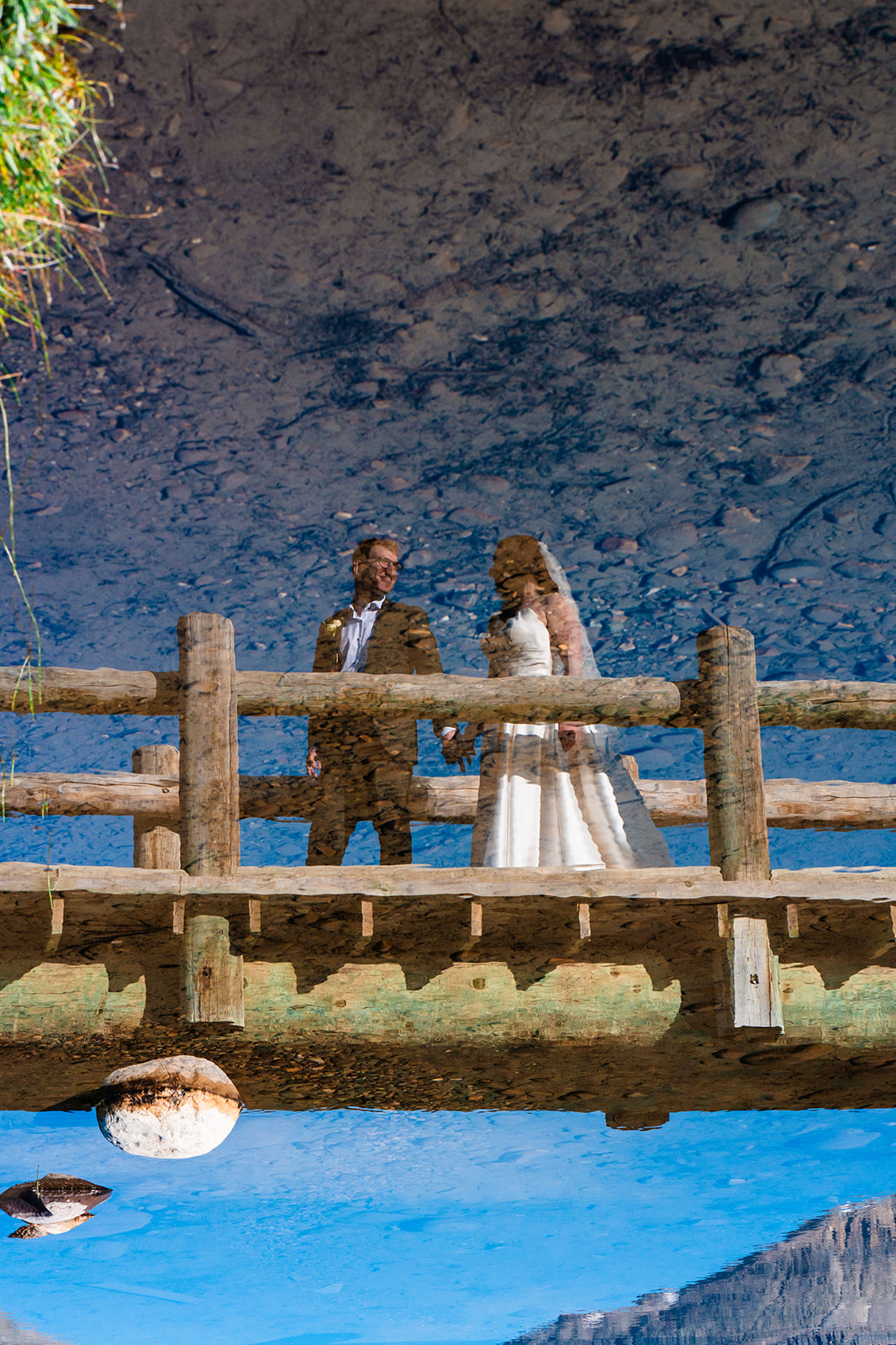 Bride and groom walking across a bridge in Banff, Alberta