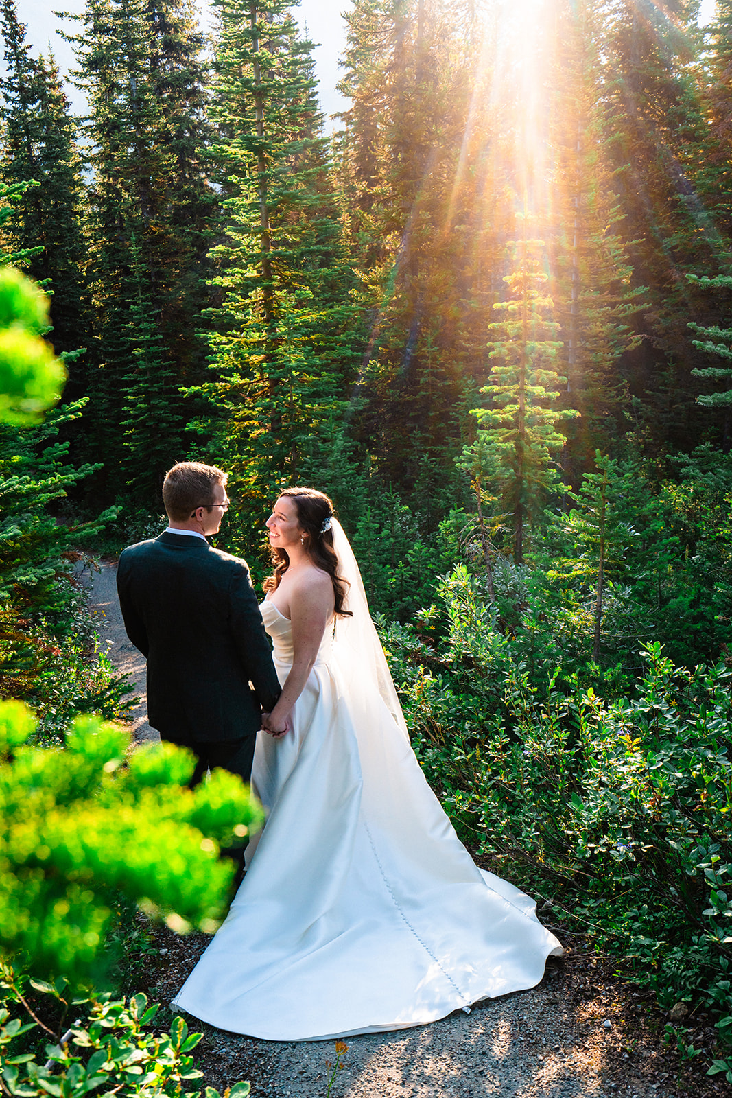 Bride and groom looking at one another endearingly in the forests of Banff