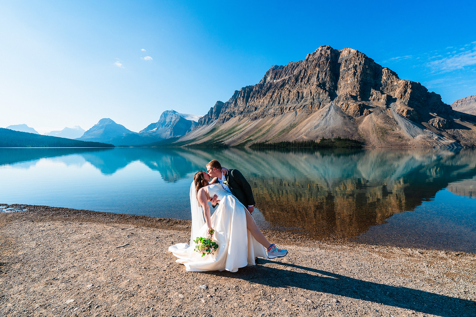 Groom dipping bride kissing her in front of a lake in Banff, Canada