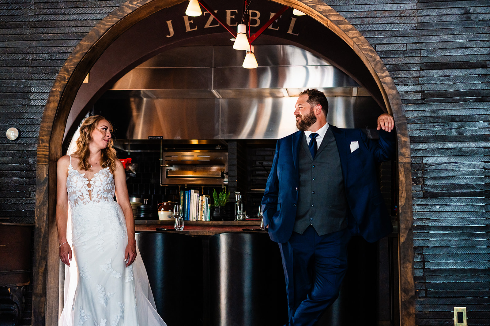 Bride and groom looking at one another posing next to a restaurant bar