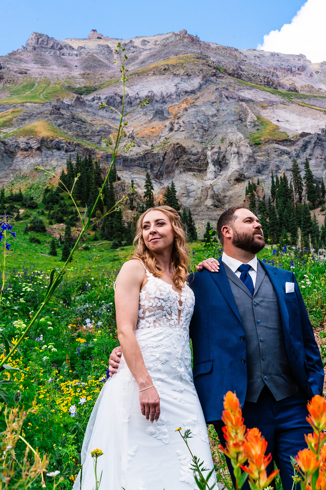 Bride and groom posing in a field of flowers and grass at Yankee Boy Basin