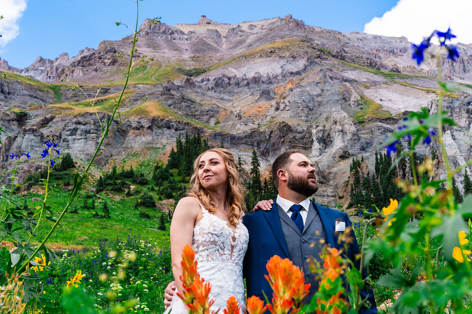 Bride and groom posing in a field of flowers and grass at Yankee Boy Basin