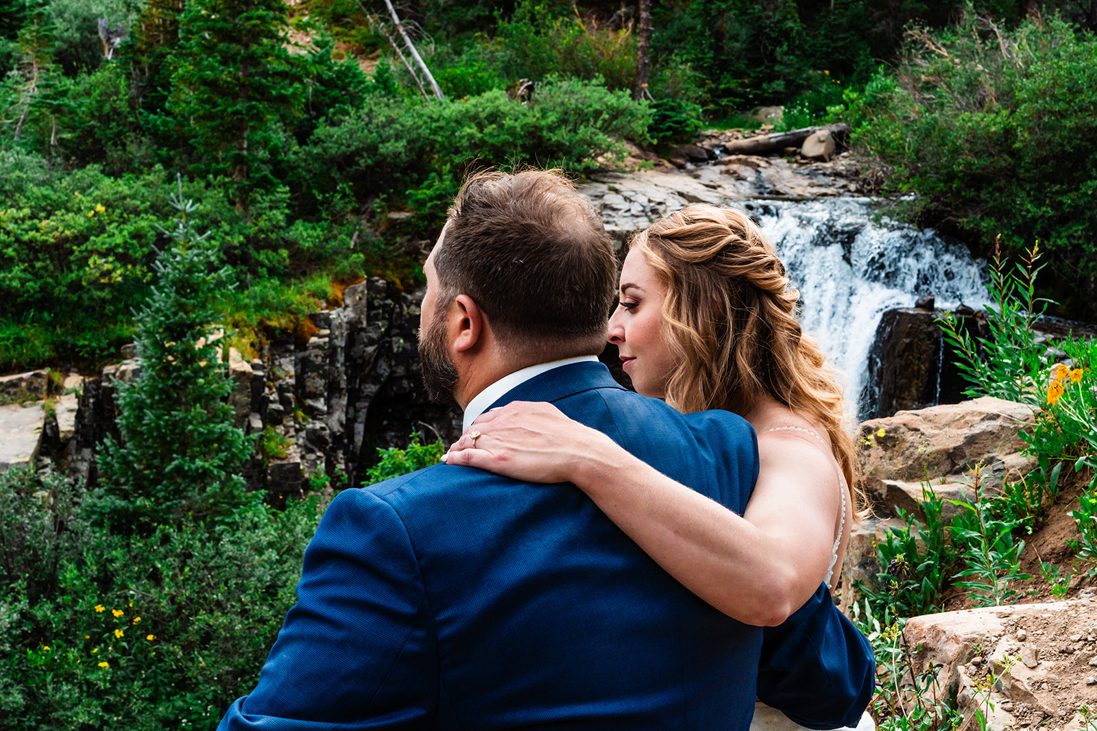 Bride and groom looking at a waterfall during their elopement and wedding at Yankee Boy Basin
