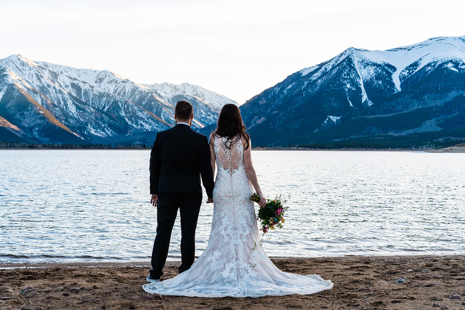 Bride and groom holding hands standing side by side at Twin Lakes
