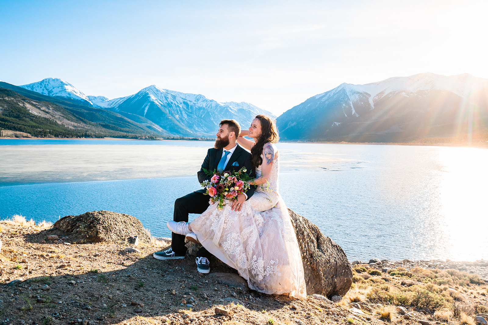 Bride and groom sitting on rock in front of the Twin Lakes