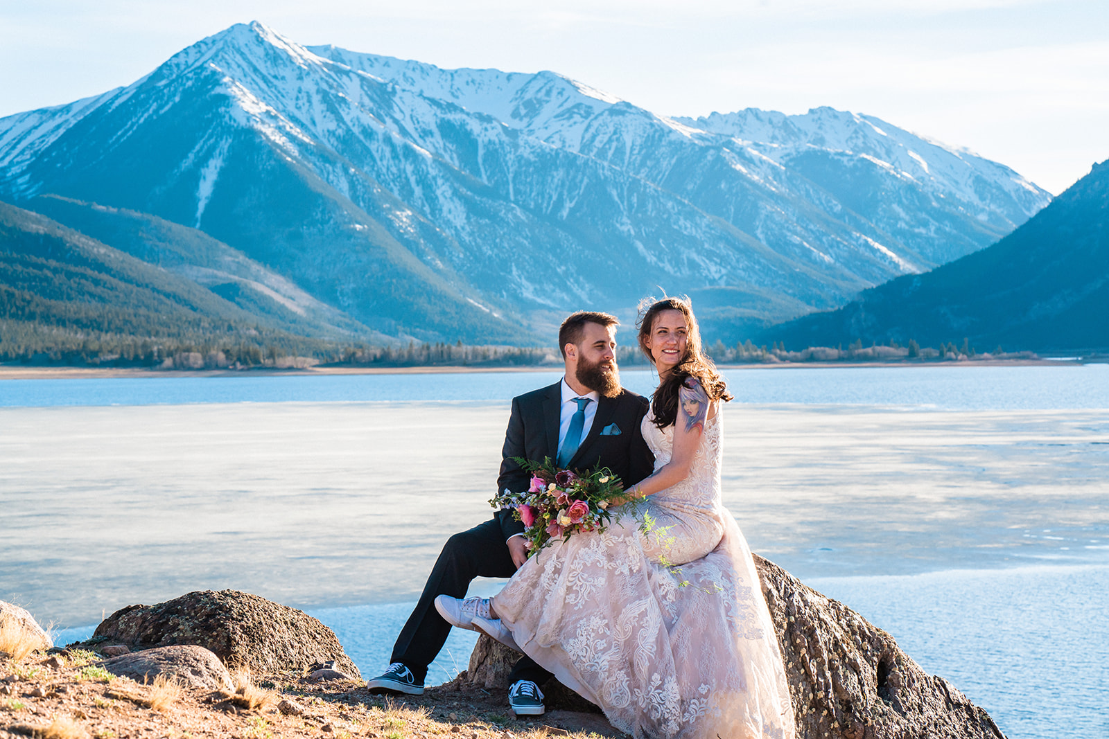 Bride and groom sitting on rock in front of the Twin Lakes