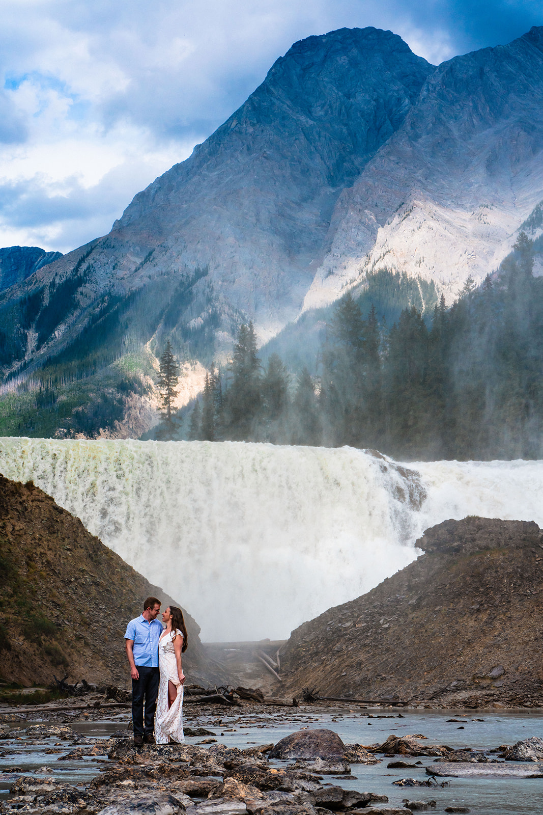 Bride and groom standing near waterfall in Yoho National Park of Canada