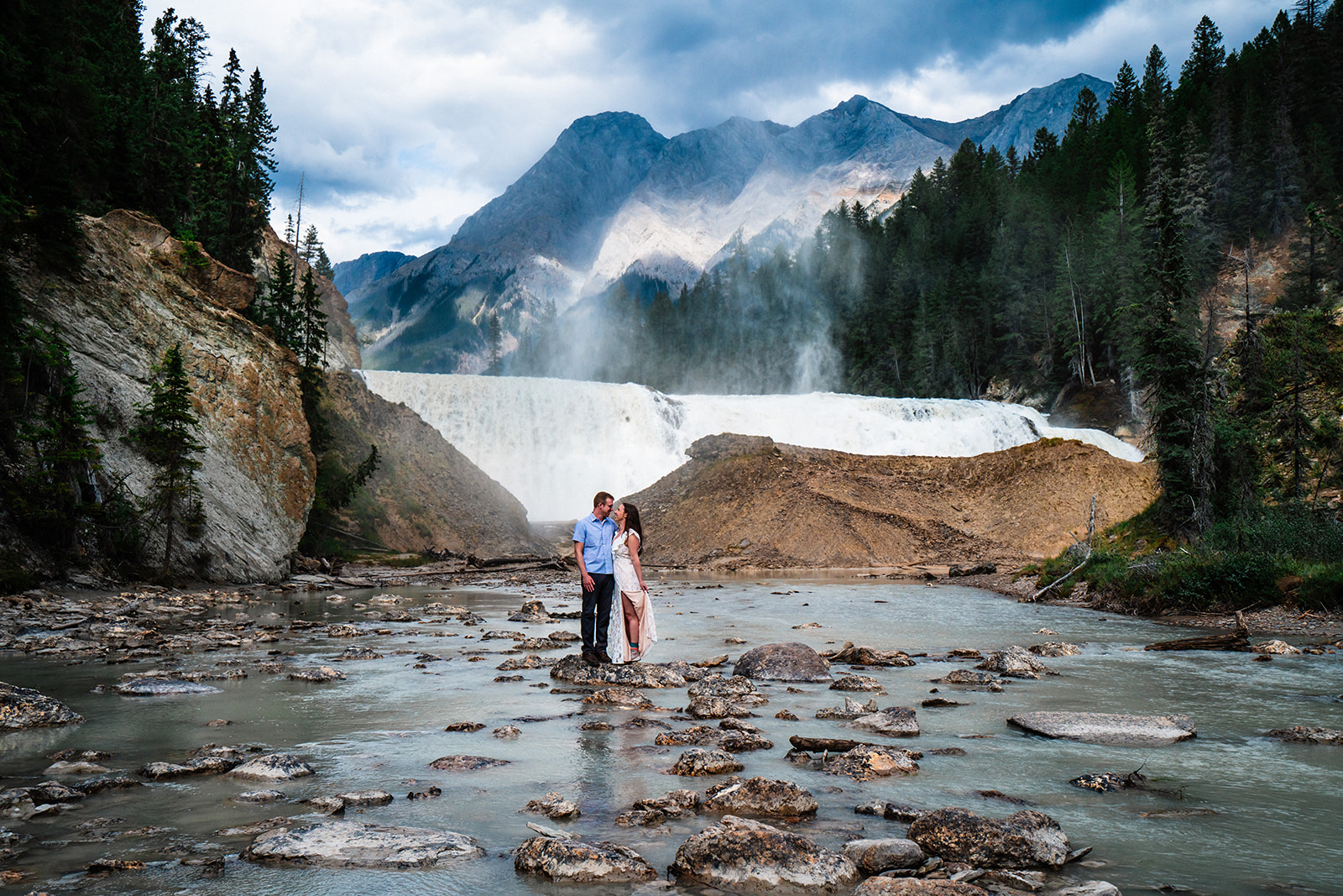 Bride and groom standing near waterfall in Yoho National Park of Canada
