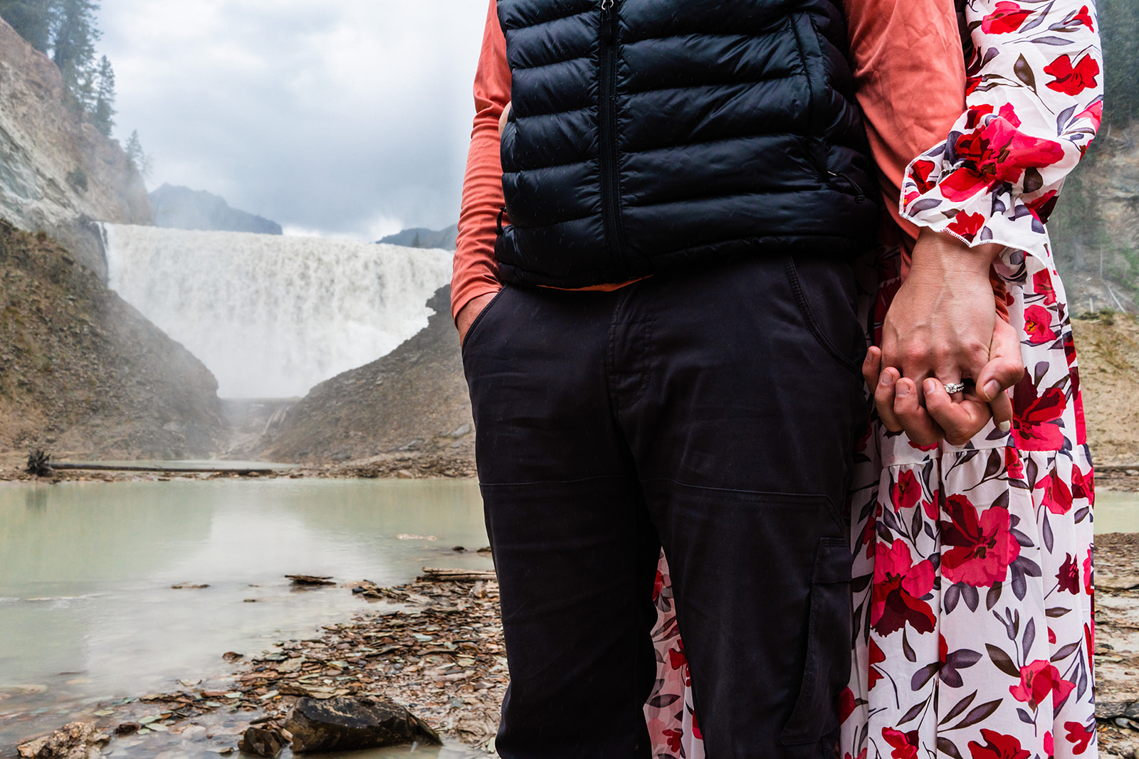Bride and groom holding hands near the waterfalls of Canada