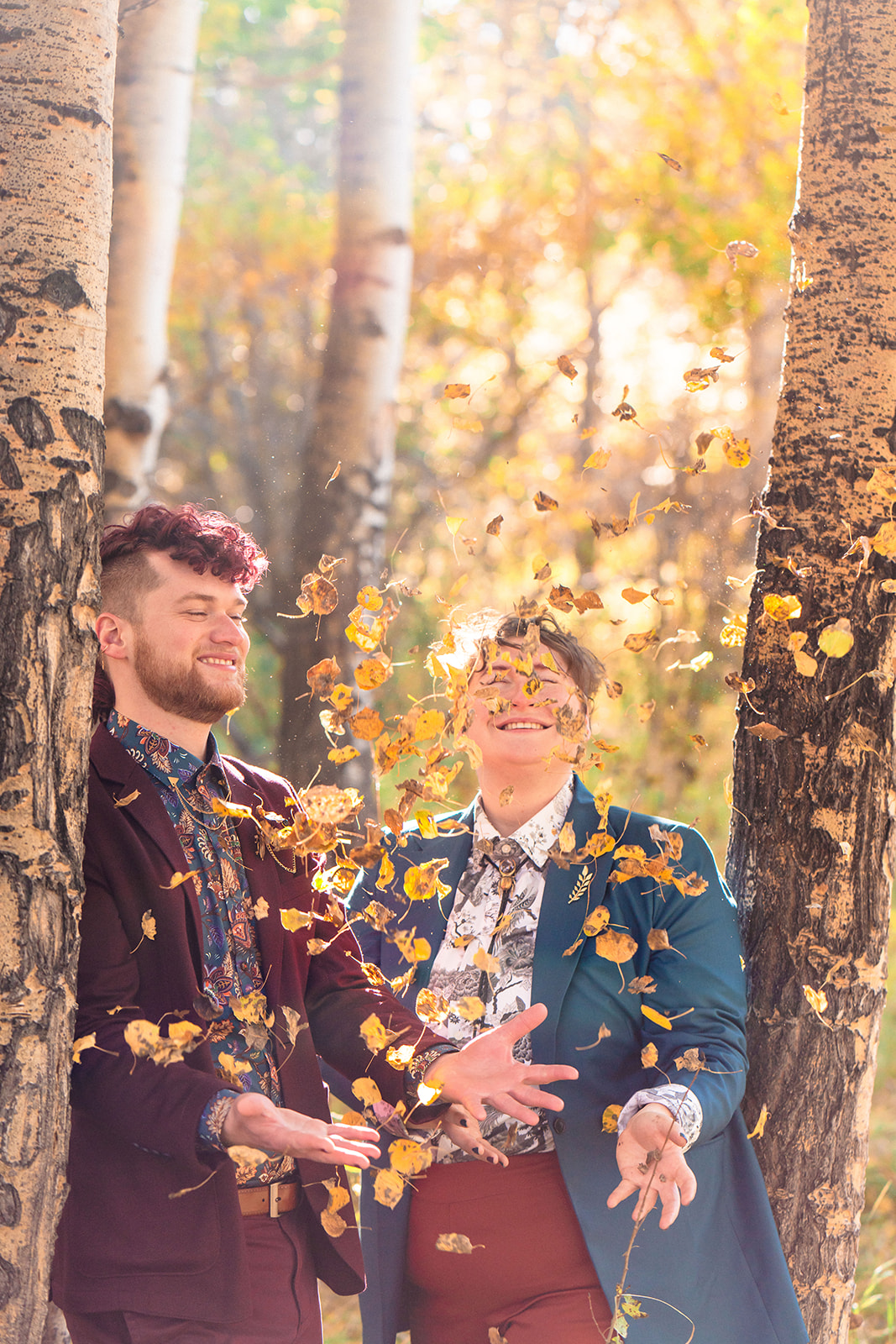 Newlyweds playing with fall leaves in the mountains of Colorado