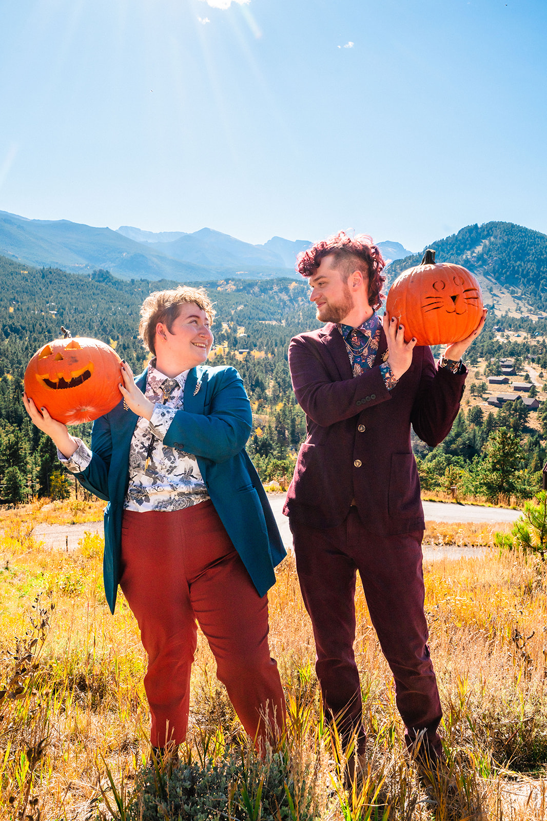 Newlyweds holding up carved pumpkins during their Fall Brainard Lake elopement