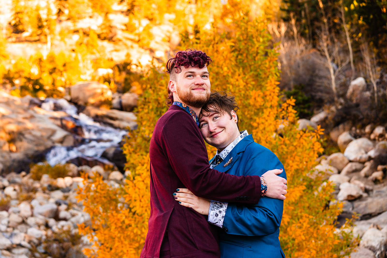 Newlyweds hugging one another smiling at Brainard lake in Autumn