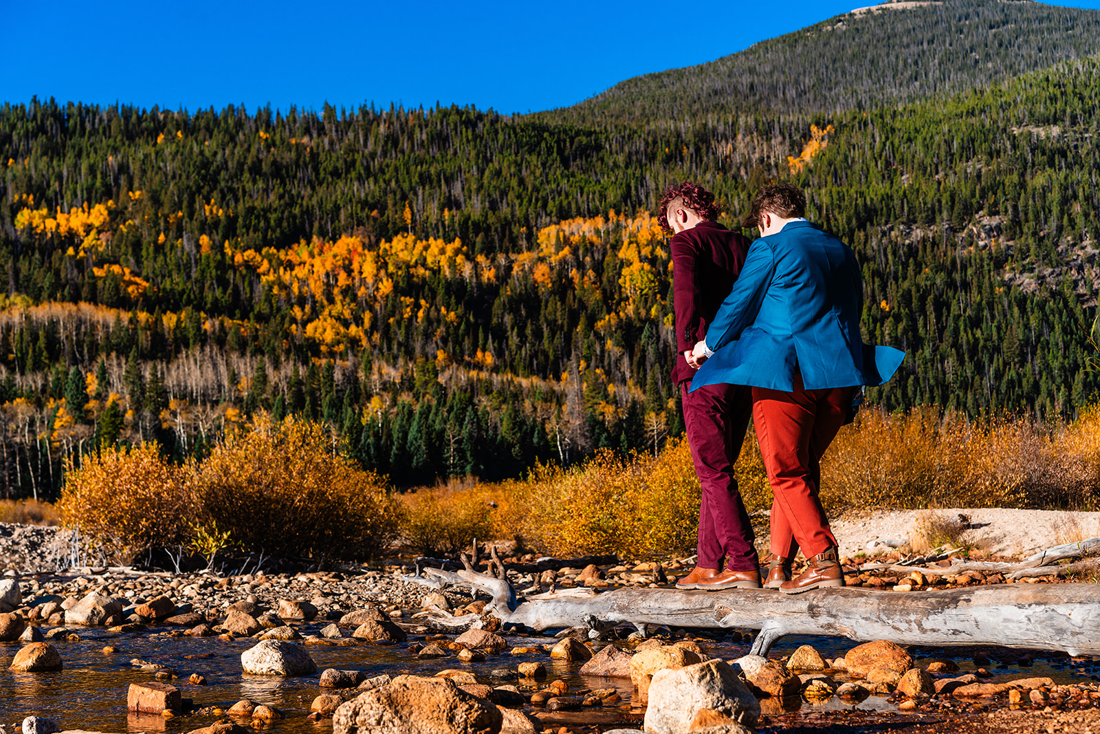 Couple holding hands walking on rocks at Brainard lake during the Fall