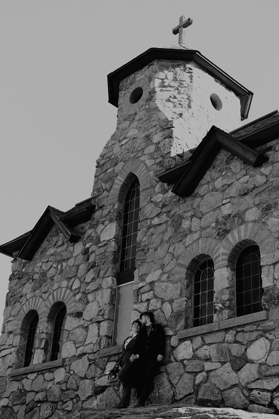 Black and white photo of newlywed coupls standing in front of a stunning church in the mountains of Colorado near Brainard Lake