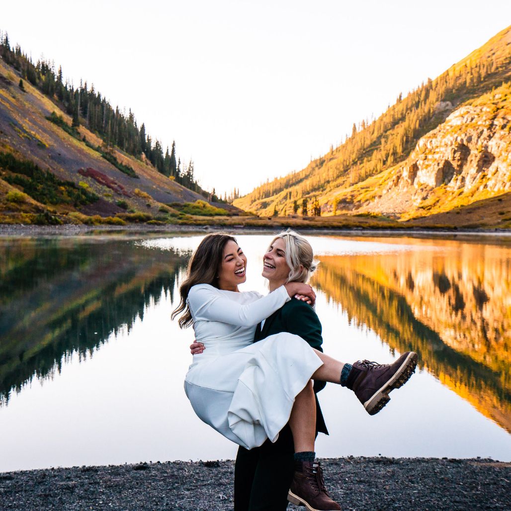 a woman carrying her bride in front of the lake and Colorado mountains