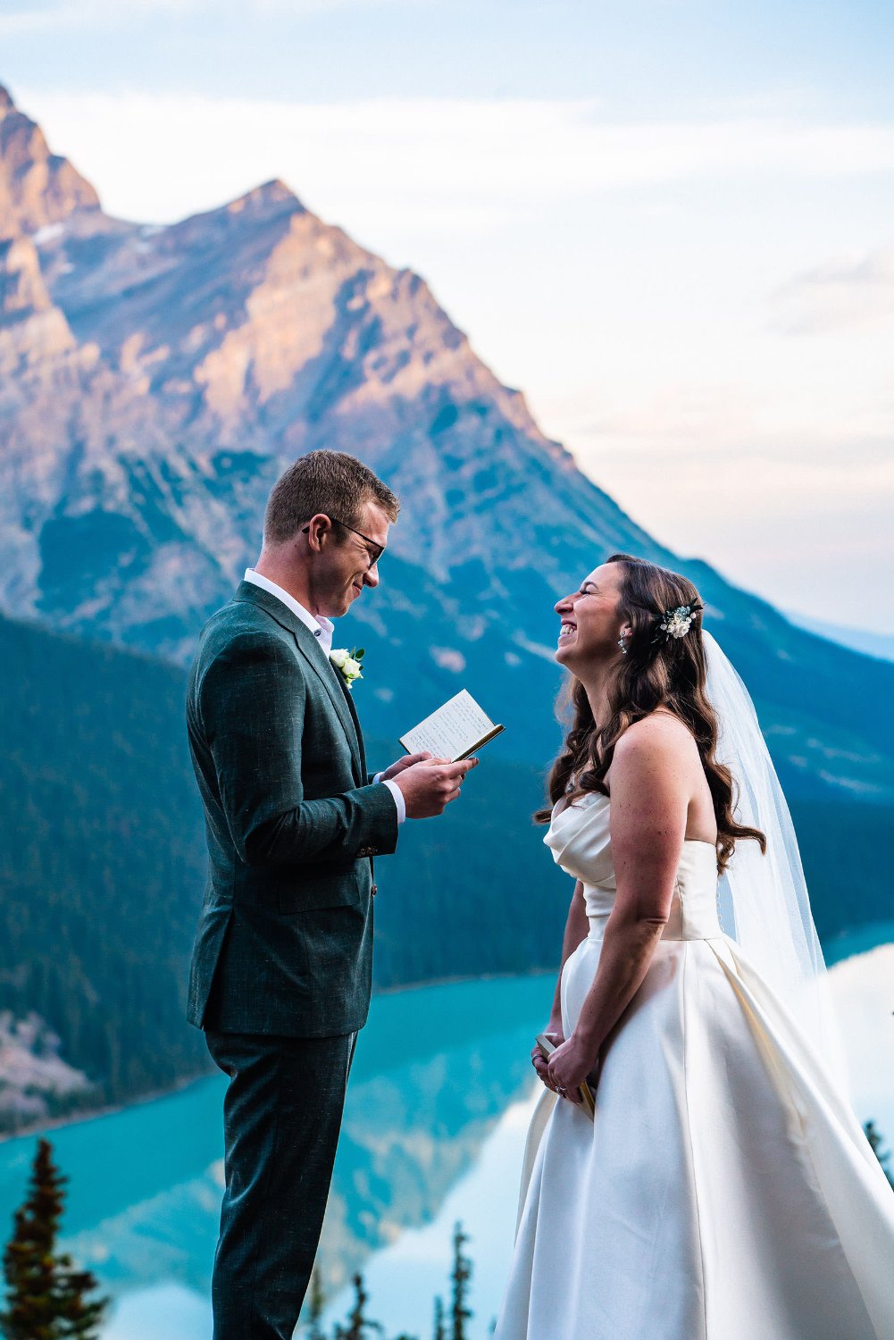A bride and groom capture their heartfelt elopement vows on top of a mountain overlooking a picturesque lake.
