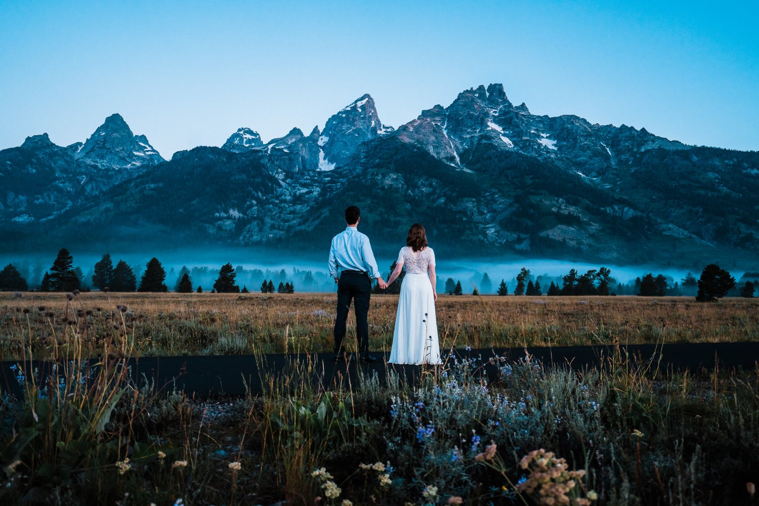 A couple stands in front of the grand teton mountains, capturing beautiful elopement photos.