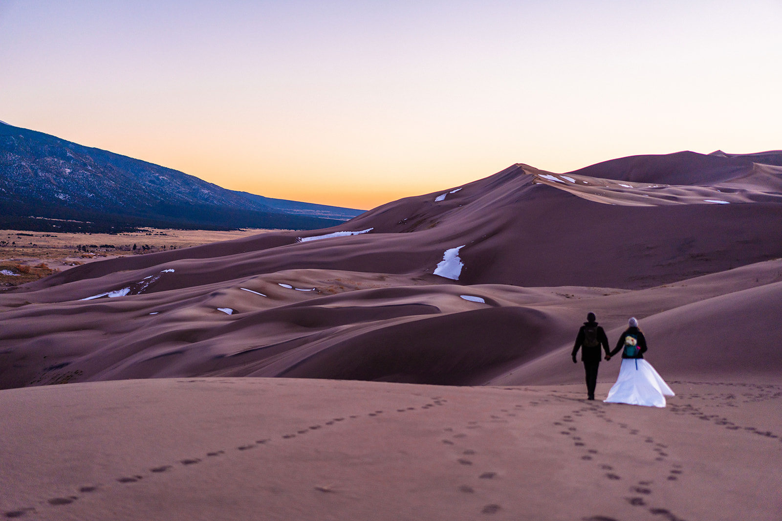 Bride and groom walking at the Great sand dunes in colorado.