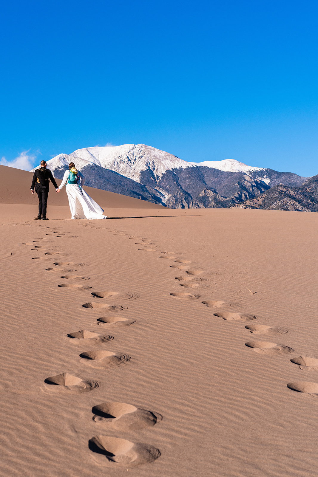 A bride and groom walking in the sand during their Great Sand Dunes elopement
