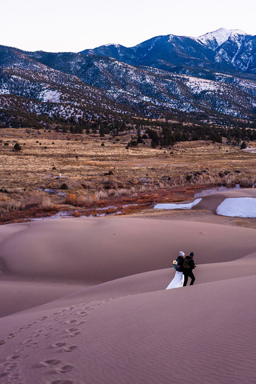 A bride and groom walking through the sand dunes at great sand dunes national park.