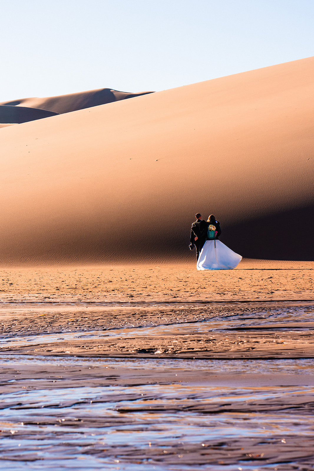 Bride and groom walking in Sand dunes in the desert.