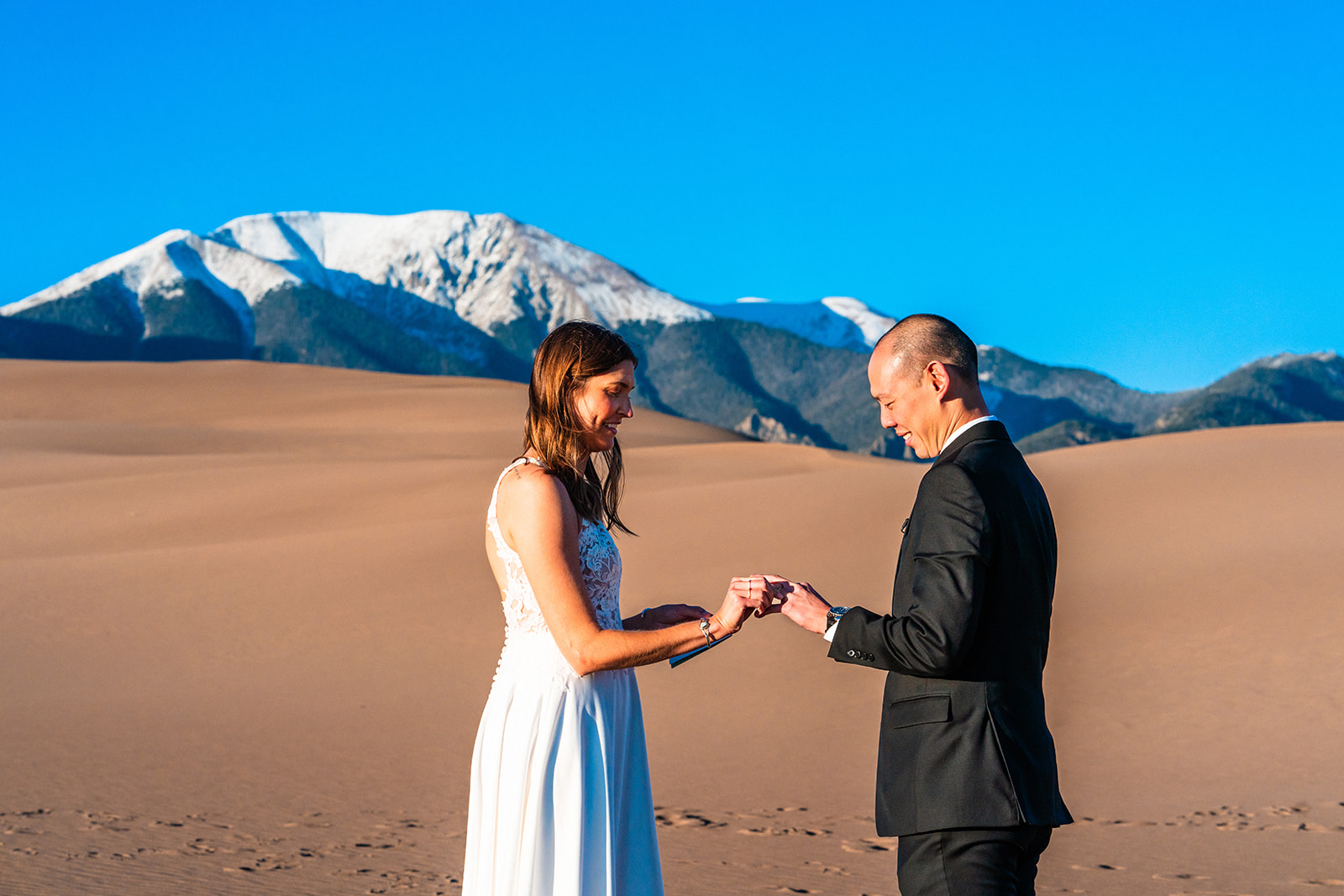 Bride and groom exchanging vows and rings during their Great sand dunes elopement.