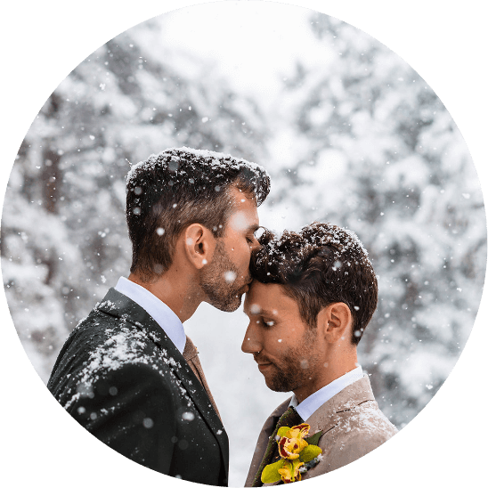 A man kisses his groom on the forehead in the snow