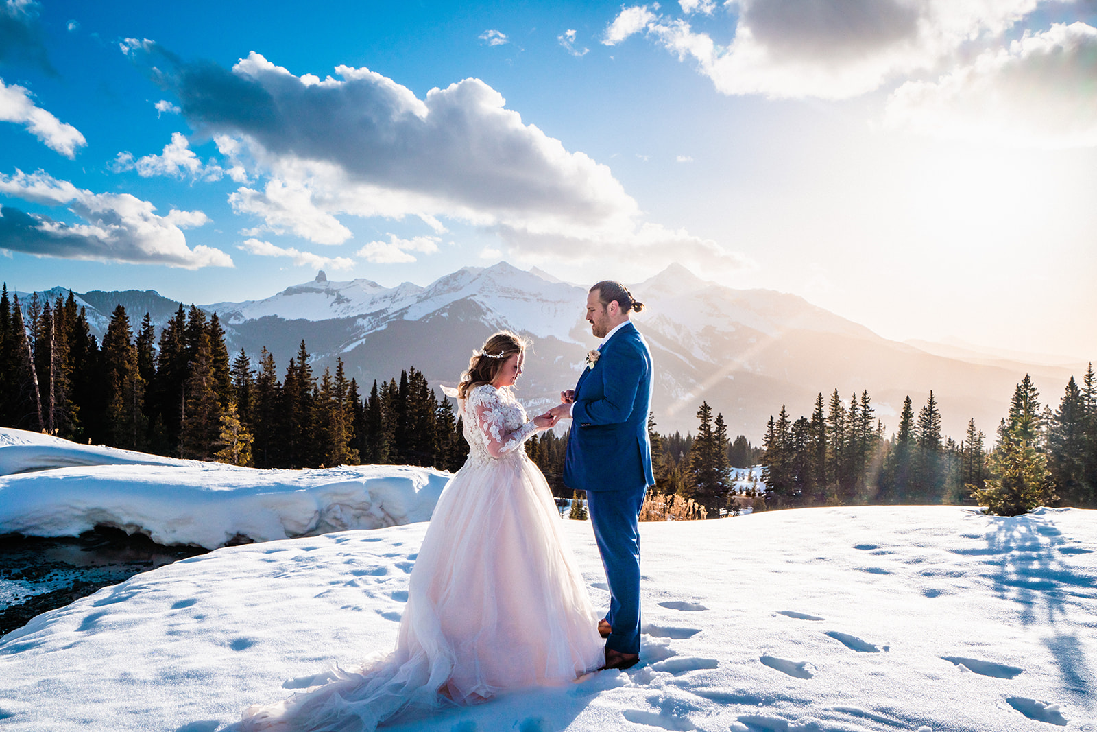 A bride and groom standing in the snow with mountains in the background, captured by a Telluride elopement photographer.