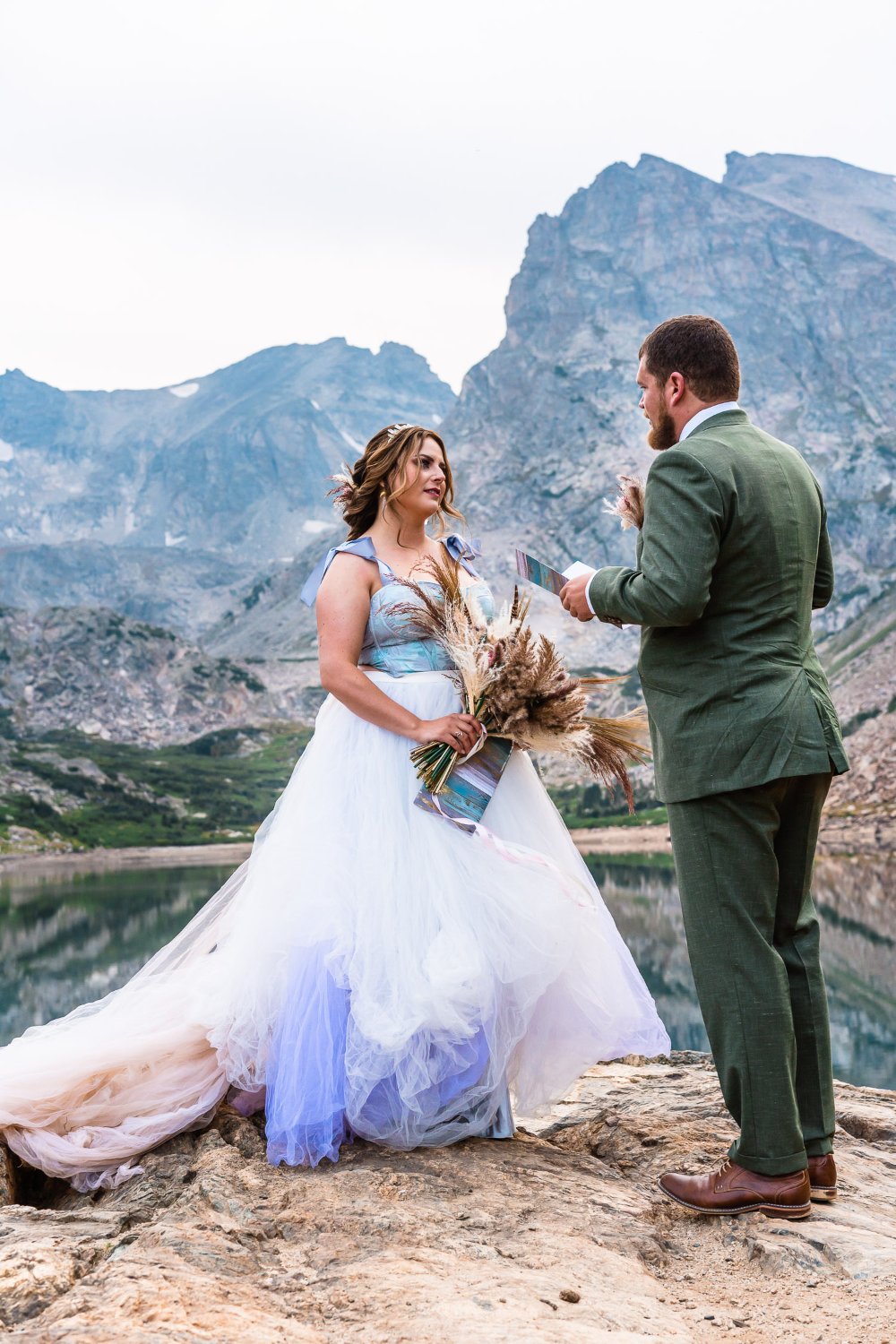 Elopement photos capture a bride and groom exchanging vows in front of a breathtaking mountain lake.