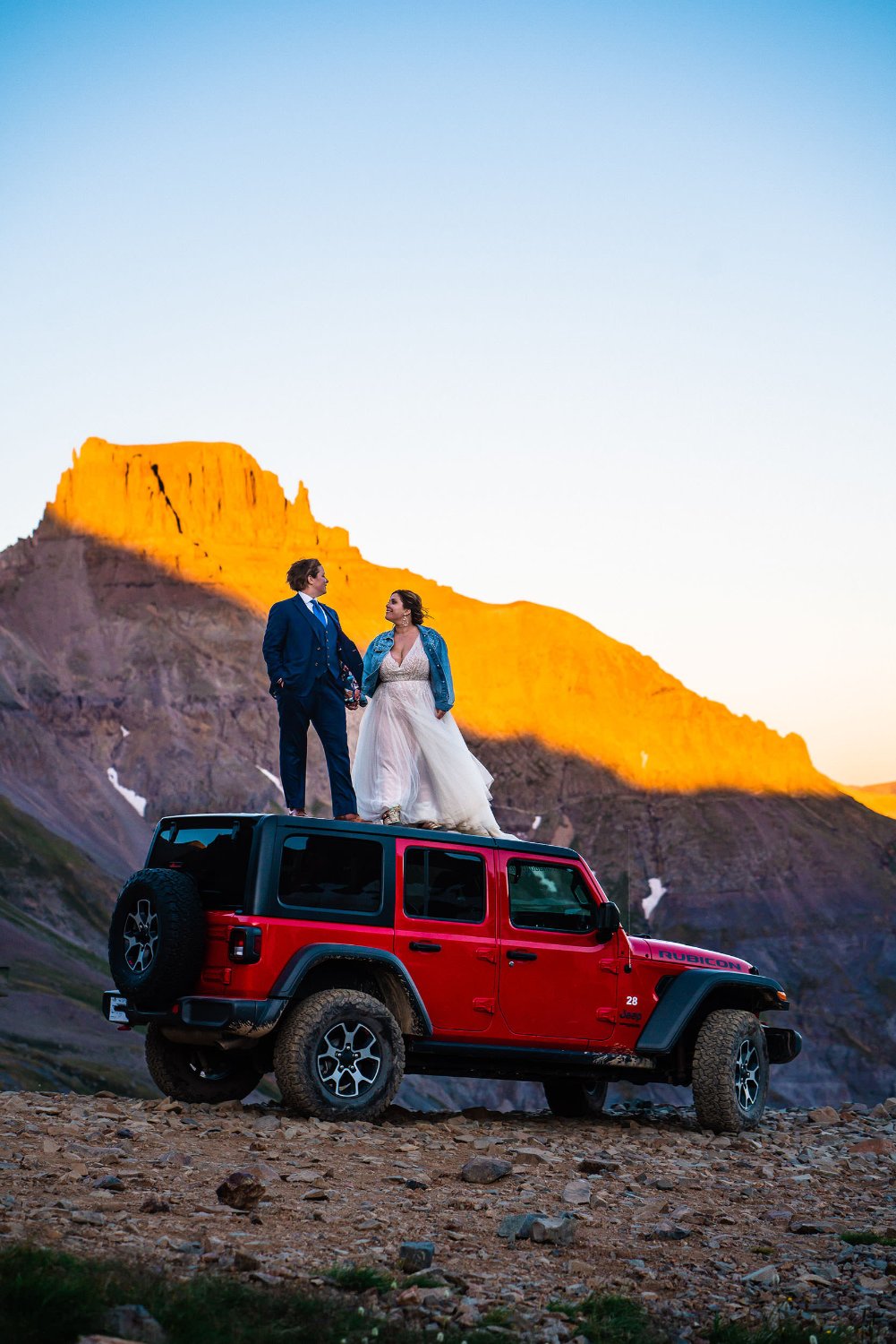 Elopement photos of a bride and groom standing on top of a jeep.