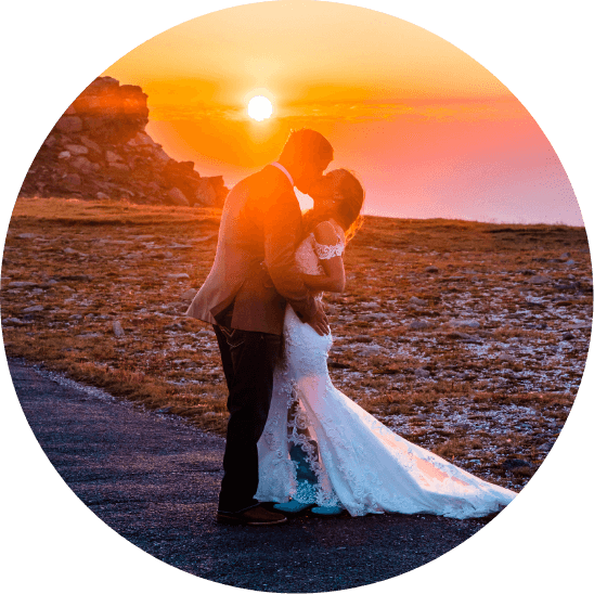 A bride and groom kiss at sunset