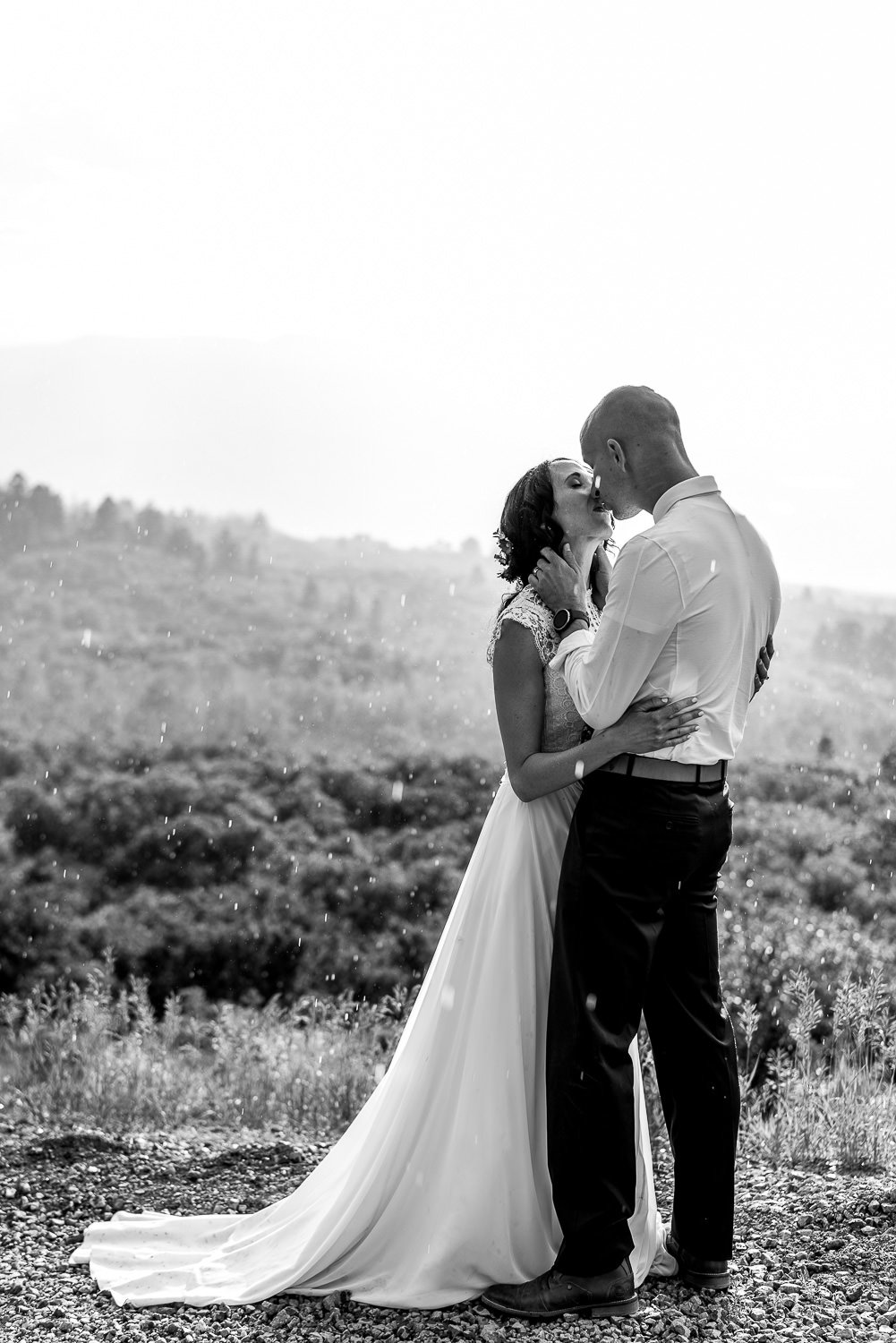 An intimate elopement photo capturing a bride and groom kissing on a picturesque hillside.